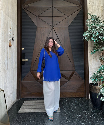 Inara cobalt crepe kurta styled with ivory cotton farsi salwar on a styled doorway